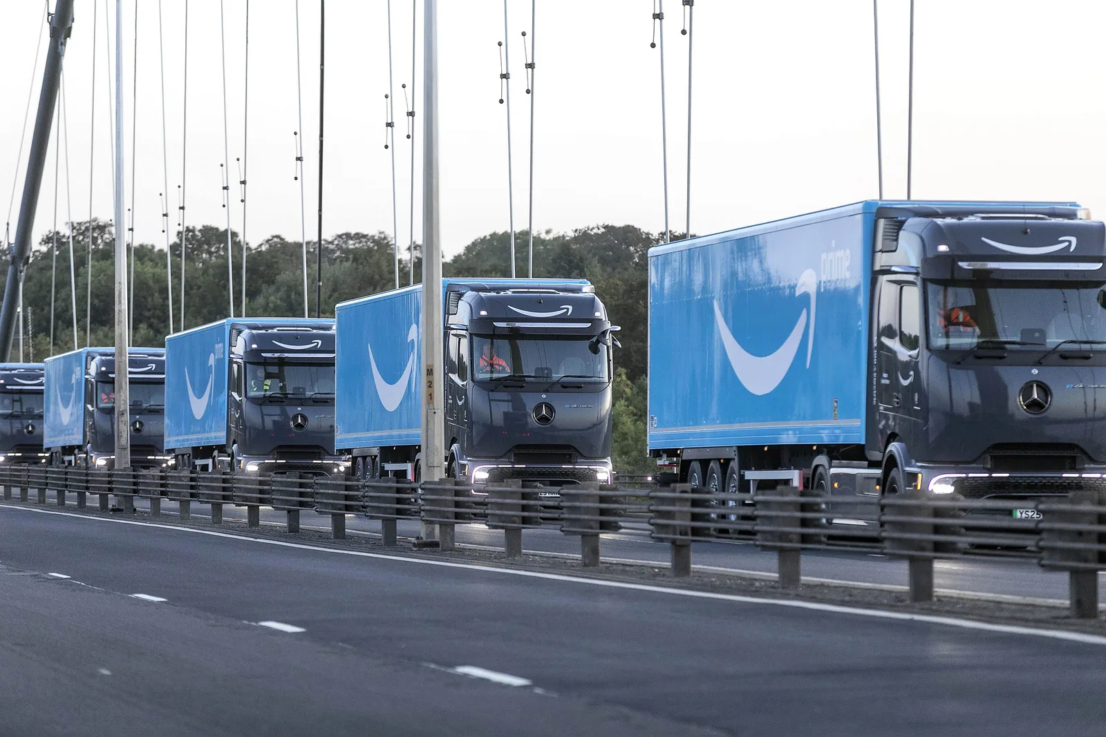 A convoy of Amazon-liveried Mercedes-Benz eActros 600 electric lorries crossing the Humber Bridge.