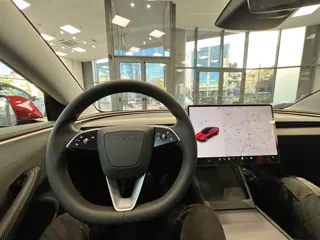 Steering wheel and centre display inside a Tesla Model 3.