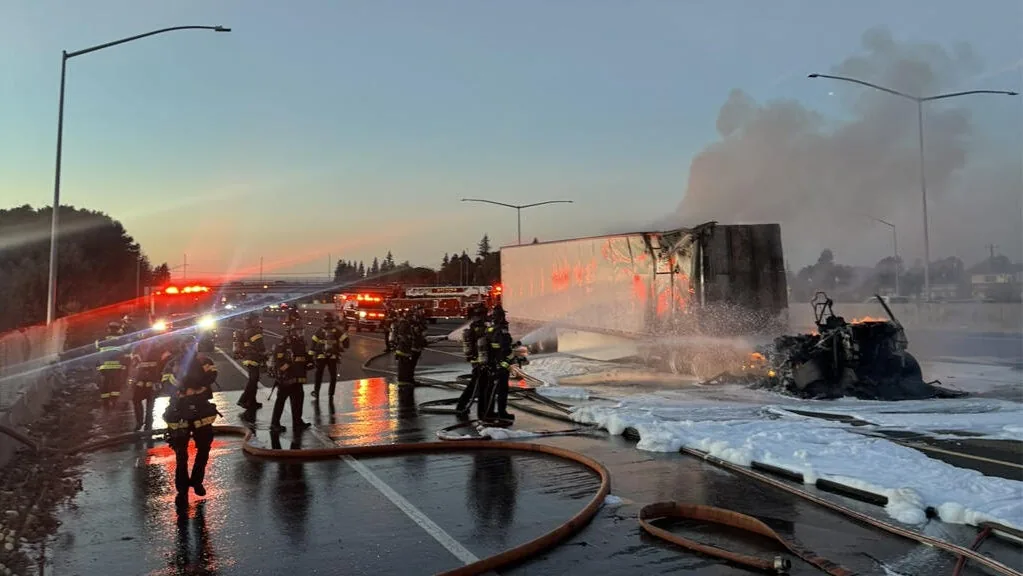 Firefighters spray water and foam at the burning Tesla Semi tractor beside its trailer on Interstate 880 in Hayward.